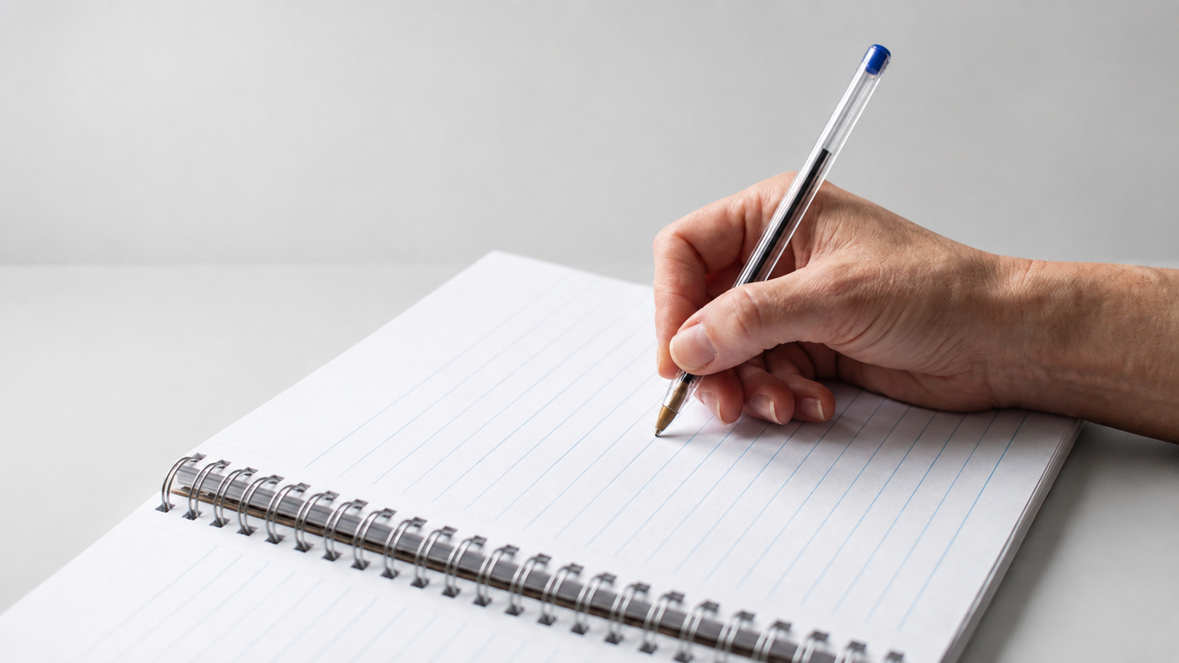 A hand writing in a notebook with a blue pen, representing the project brief